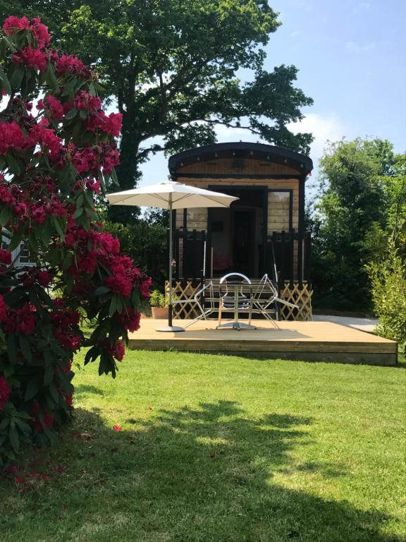een prieel met een tafel en een parasol bij Roul'hôte du bout du monde in Landévennec