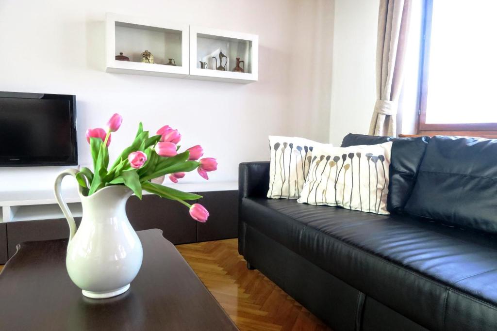 a living room with a black couch and a vase with pink flowers at Hiša Kala in Kobarid