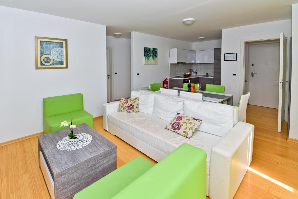 salon z białą kanapą i zielonymi krzesłami w obiekcie Apartmani Astrado Petrčane w Petrčane