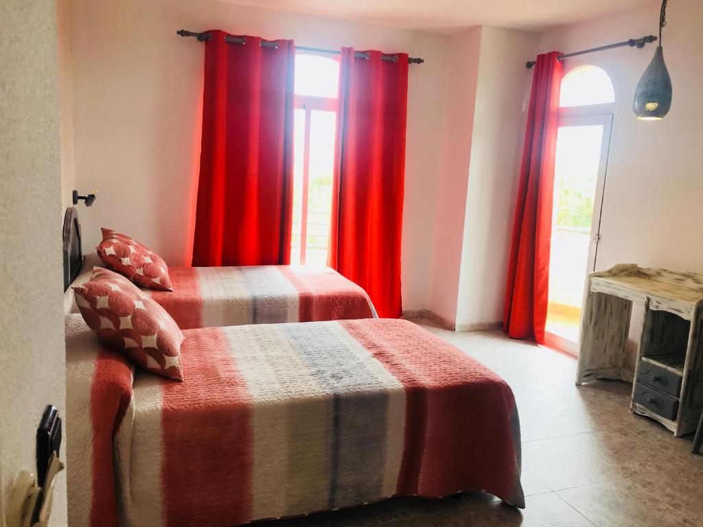 1 dormitorio con 2 camas y cortinas rojas en Hospedium Hotel Twist, en Torredonjimeno