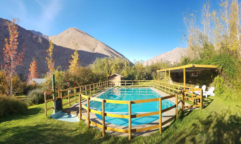 a swimming pool in a yard with mountains in the background at Cabañas Los Sauzales in Pisco Elqui