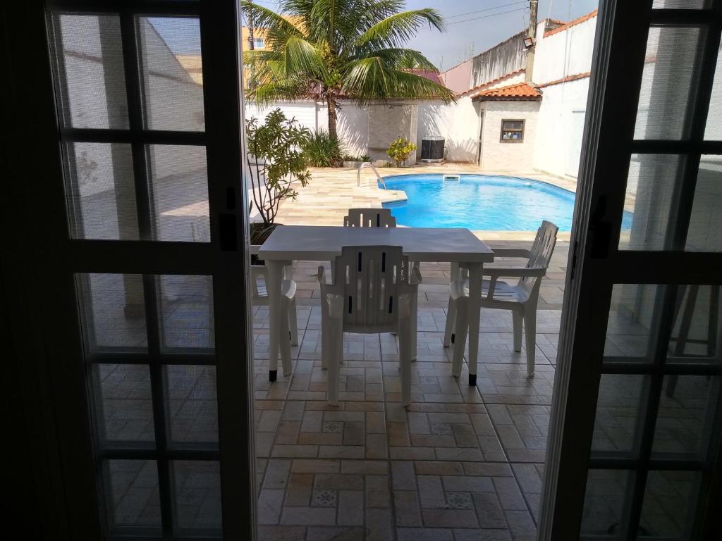 a table and chairs in front of a swimming pool at Casa Itanhaém Pé na Areia in Itanhaém