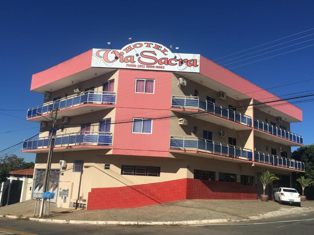 a pink building with a sign on it at Hotel Via Sacra in Trindade