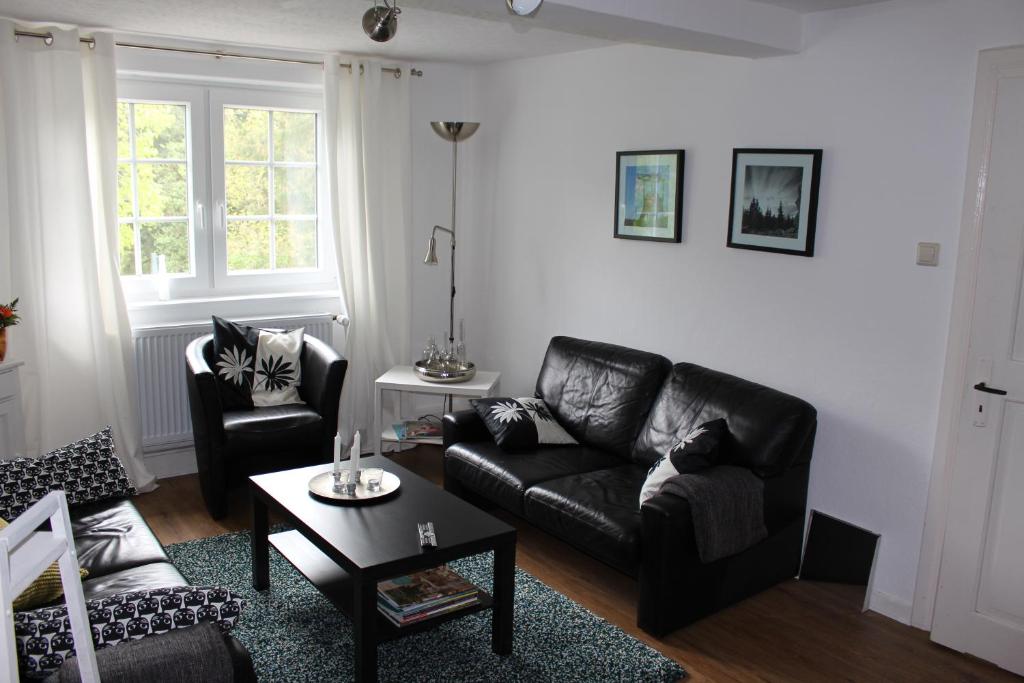 a living room with a black leather couch and a table at Zuhause mit nordischen Charme in Clausthal-Zellerfeld