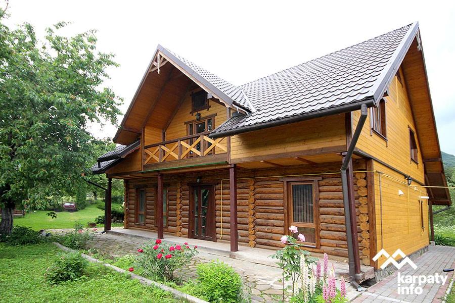 a wooden house with a gambrel roof at Nad Cheremoshem in Tyudov