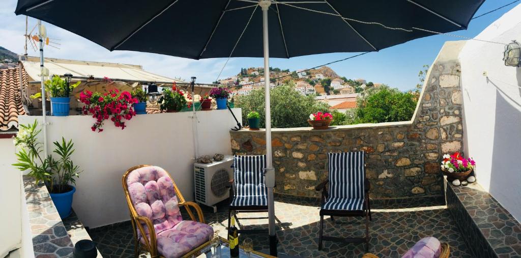 a patio with two chairs and an umbrella at Maria's House in Hydra