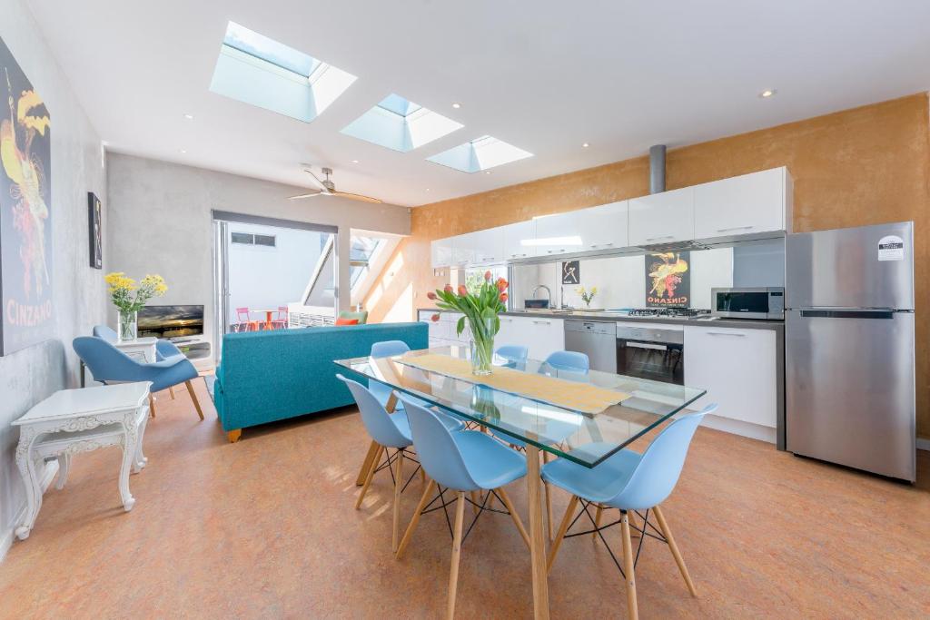 uma cozinha e sala de jantar com uma mesa de vidro e cadeiras azuis em Chic East Sydney Pad em Sydney