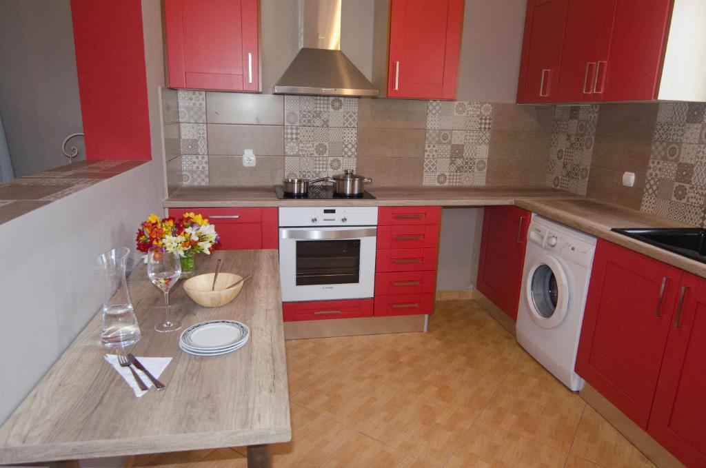 a kitchen with red cabinets and a table with flowers on it at Marina's House in Khelmáta