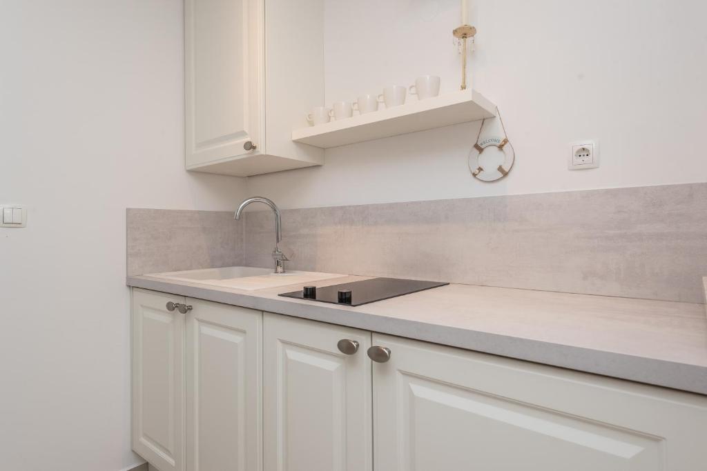 una cucina con armadi bianchi e lavandino di Villa Bella with pool a Novalja (Novaglia)