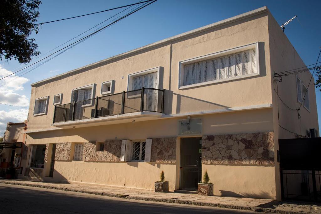 a white building with a balcony on a street at Luna Serrana Hotel in Capilla del Monte