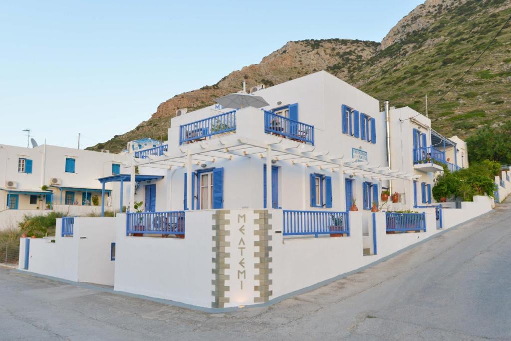 a white building with blue balconies on a street at Meltemi in Kamares