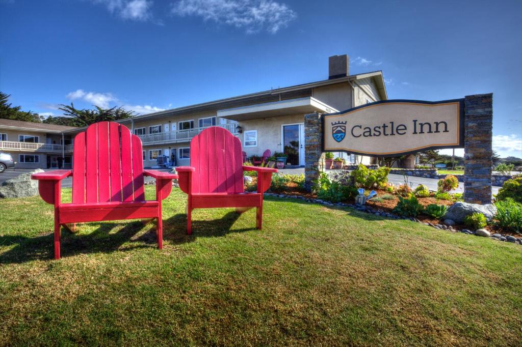 due sedie rosse sedute sull'erba di fronte a un edificio di Castle Inn a Cambria