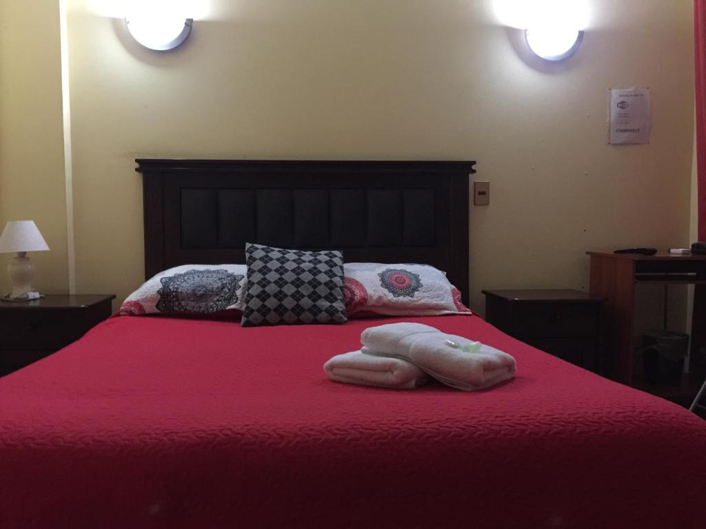 1 cama con manta roja y almohadas en Hostal Rayen Centro, en Temuco