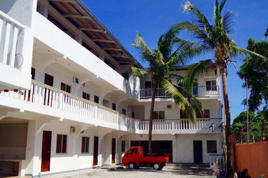 a red truck parked in front of a white building at Hana Natsu Resorts Beach & Hotel in Morong