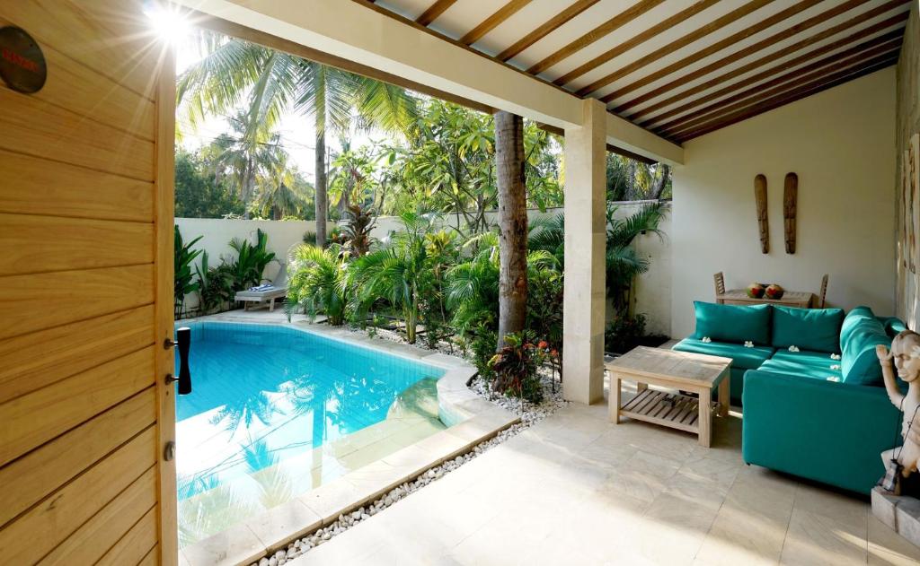 a patio with a swimming pool and a blue couch at Senang Private Villa in Gili Trawangan
