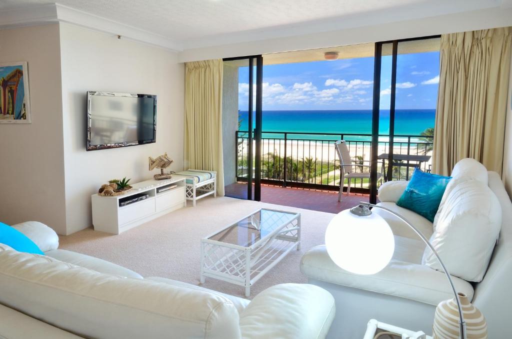 Una sala de estar con muebles blancos y vista al mar. en Blue Ocean Apartment, en Gold Coast
