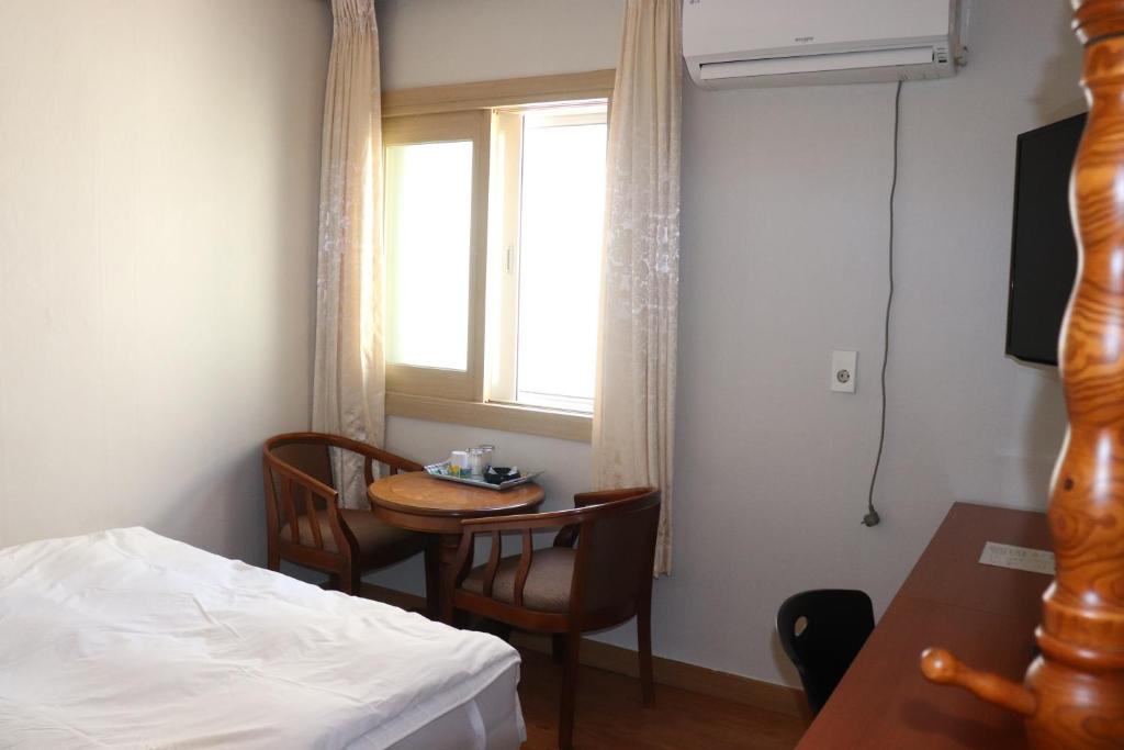um quarto com uma cama, uma mesa e uma janela em Orasung Motel em Jeju
