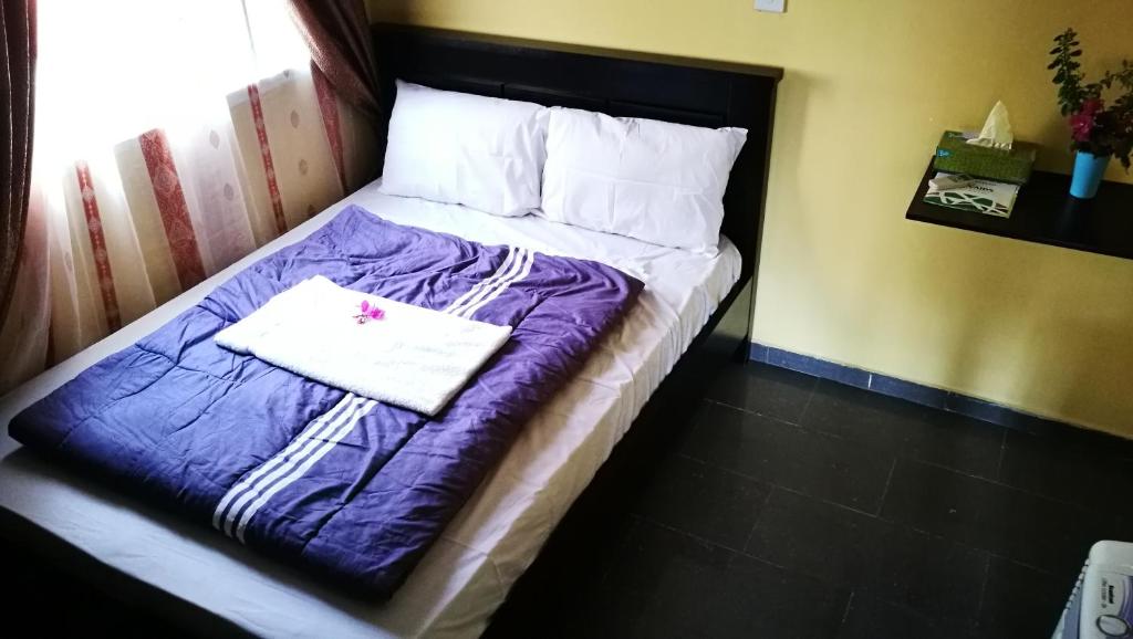 Cama en habitación con edredón púrpura en Dumeros en Abuja