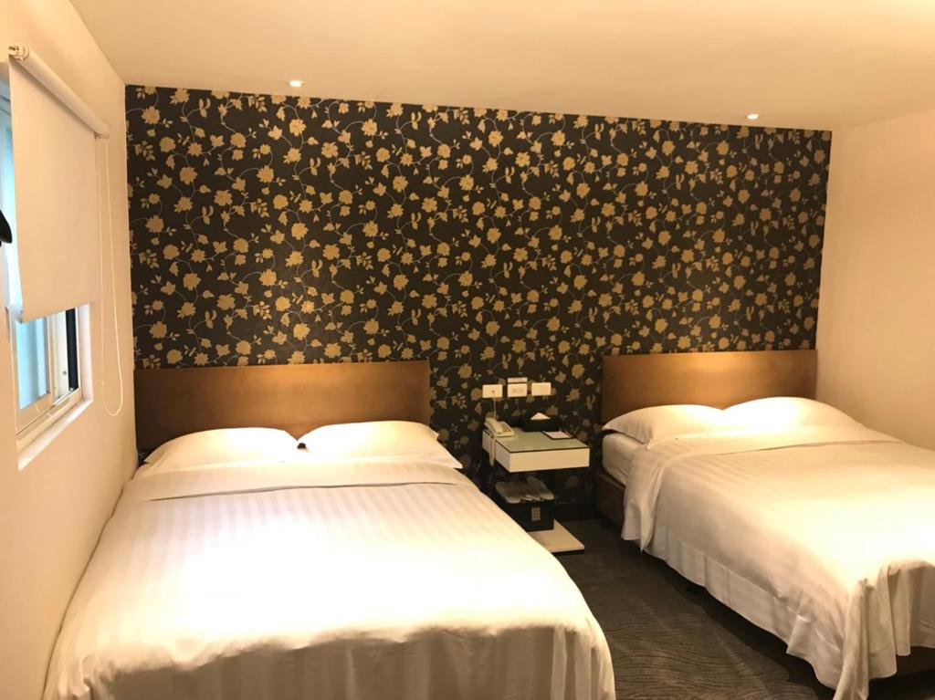 a bedroom with two beds and a wall with flowers at Hotel Puri in Taipei