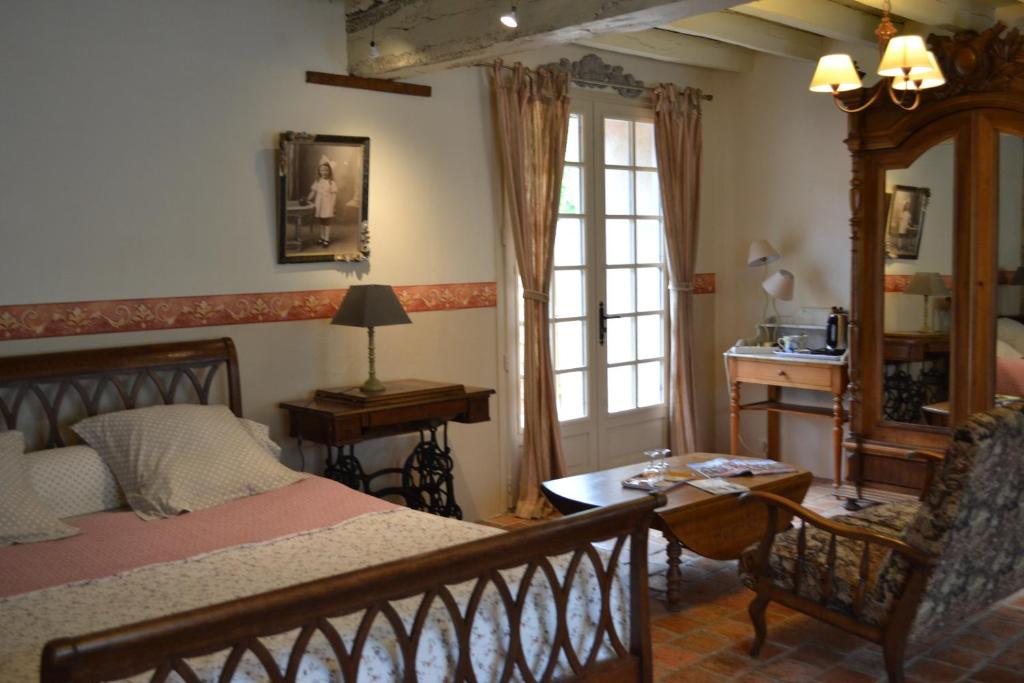 1 dormitorio con cama, mesa y ventana en Maison d'Hôtes La Chouanniere, en Brion