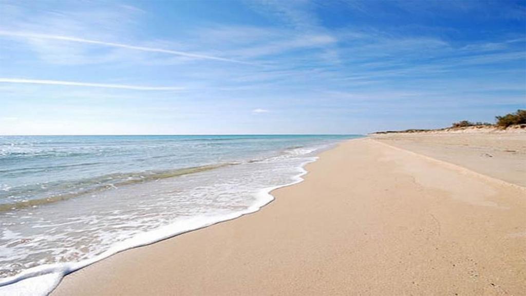 una spiaggia sabbiosa con l'oceano in una giornata di sole di Villa Azzurra a Marina di Pescoluse