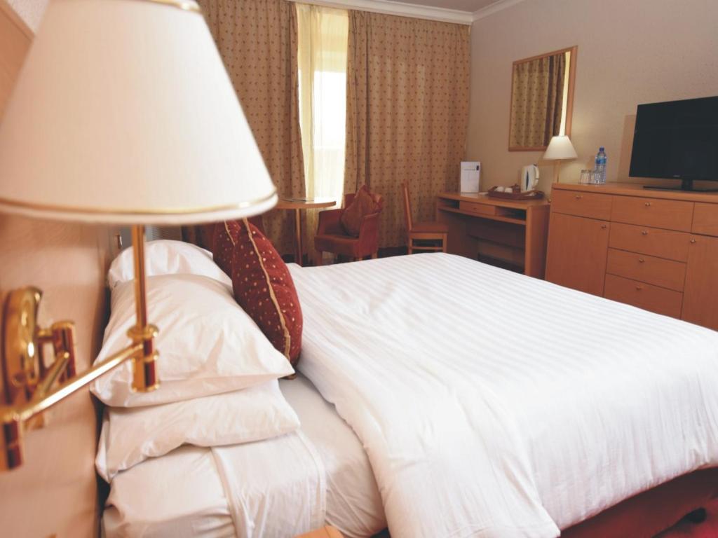 a hotel room with a white bed and a lamp at Nicon Luxury Abuja in Abuja