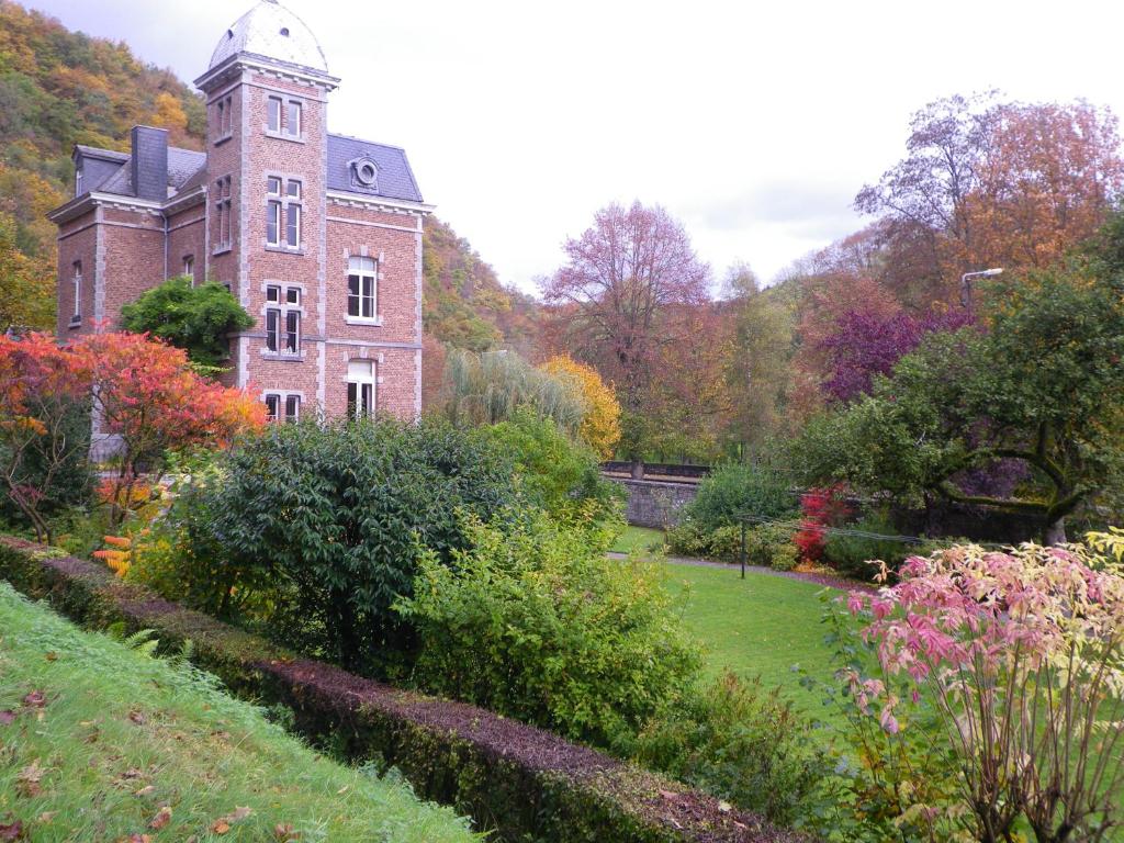 an old brick building with a clock tower in a garden at La Villa des Roses in Durbuy
