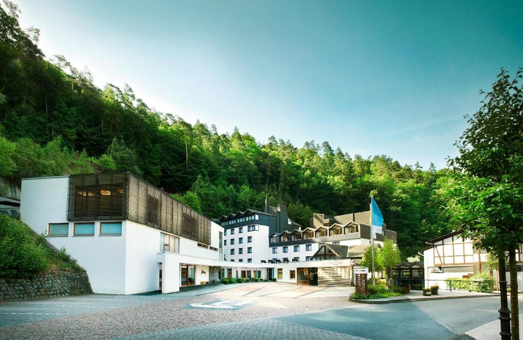 a group of buildings in front of a mountain at Hotel Zugbrücke Grenzau GmbH in Höhr-Grenzhausen
