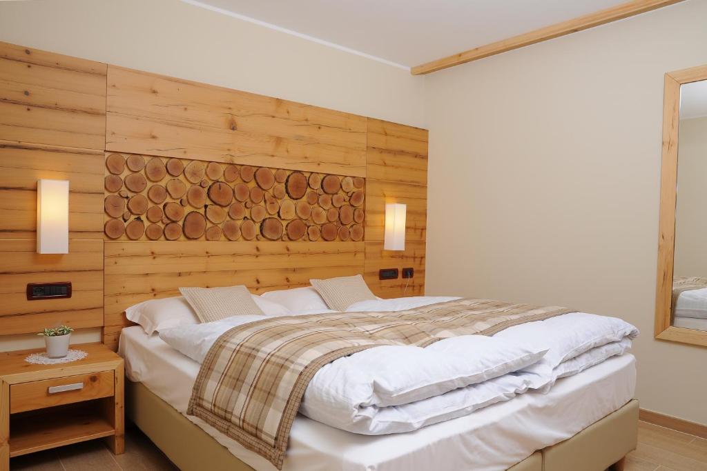 a bedroom with a large bed with a wooden wall at Residence Marisol Camere & Appartamenti - Mezzana Centre in Mezzana