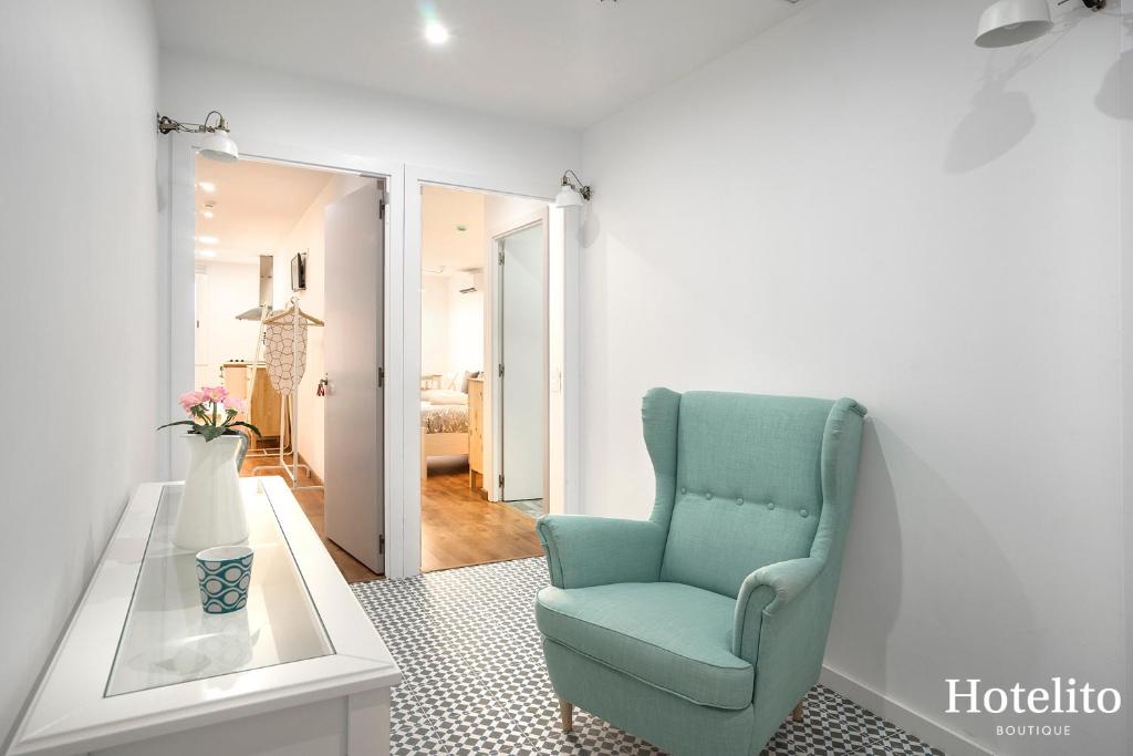 a living room with a blue chair and a table at Hotelito Boutique Mercat in Hospitalet de Llobregat