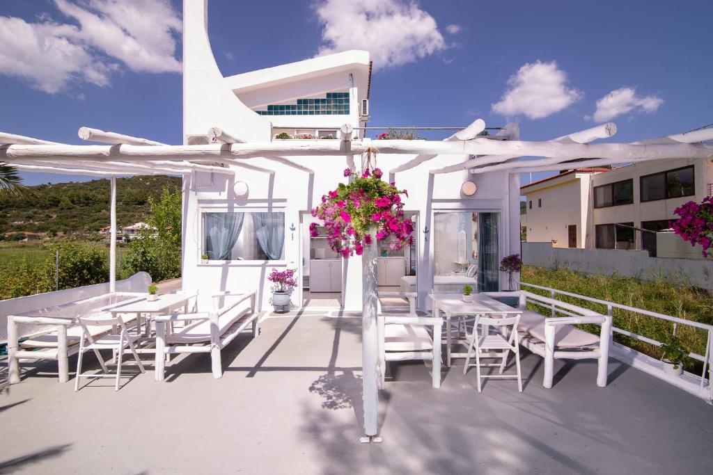 a white patio with white tables and chairs and flowers at Acapus Studios in Toroni