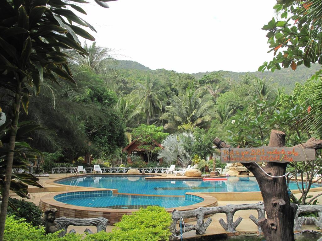 a resort with a pool with chairs and a sign at Bottle Beach 1 Resort in Bottle Beach