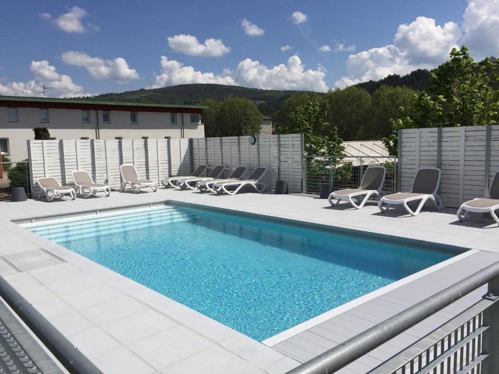 una piscina su un patio con sedie intorno di Brit Hotel Marvejols a Marvejols