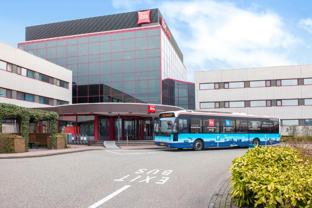 un autobús azul estacionado frente a un edificio en Ibis Schiphol Amsterdam Airport en Badhoevedorp