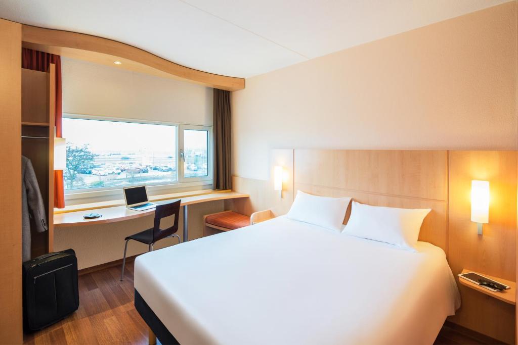 a hotel room with a large bed and a desk at Ibis Schiphol Amsterdam Airport in Badhoevedorp