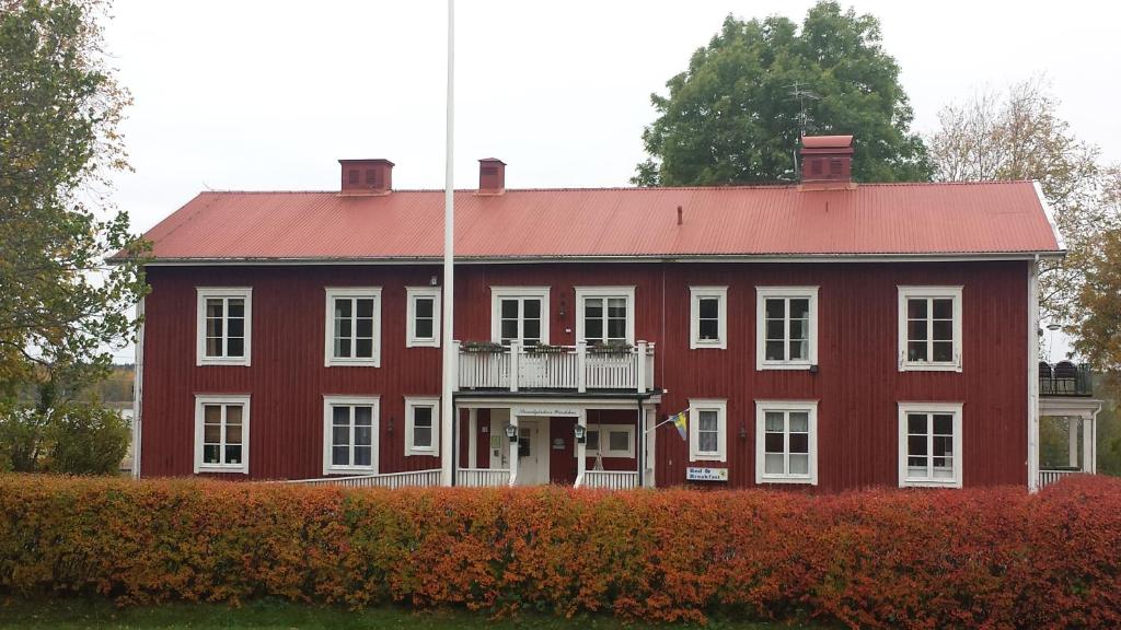 een groot rood gebouw met een balkon ervoor bij Nya Strandgårdens Wärdshus in Kristinehamn