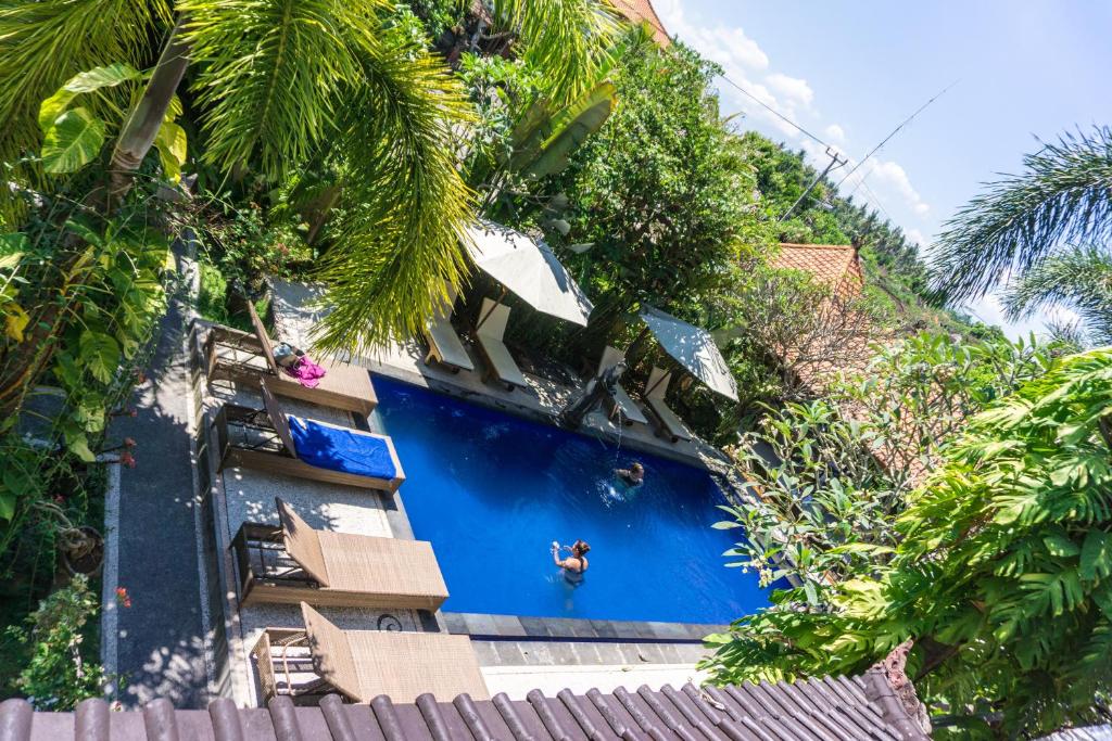 una persona parada en la parte superior de una piscina azul en Gangga Blessta Hotel, en Ubud