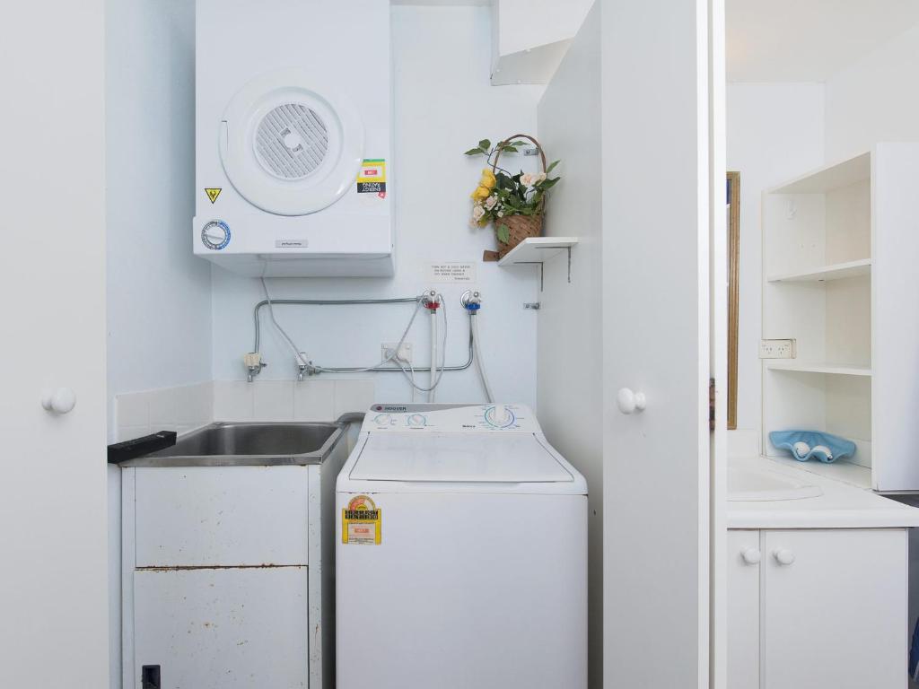 a small kitchen with a sink and a washing machine at Foreshore Paradise Nelson Bay in Nelson Bay