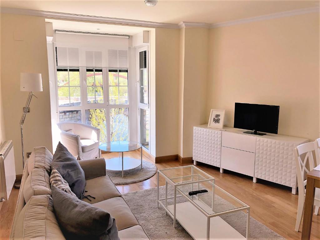 a living room with a couch and a tv at Apartamentos Del Pisuerga in Cervera de Pisuerga