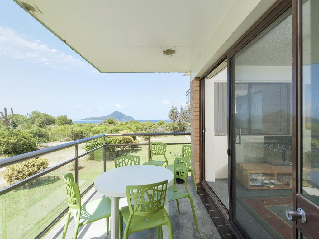 a patio with a table and chairs on a balcony at Foreshore Paradise Nelson Bay in Nelson Bay