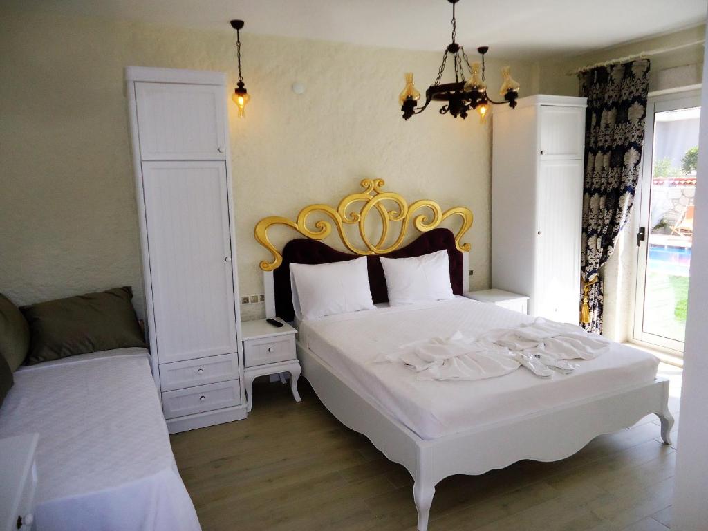 a bedroom with a white bed with a gold headboard at Grand Alaçatı Butik Hotel in Alaçatı