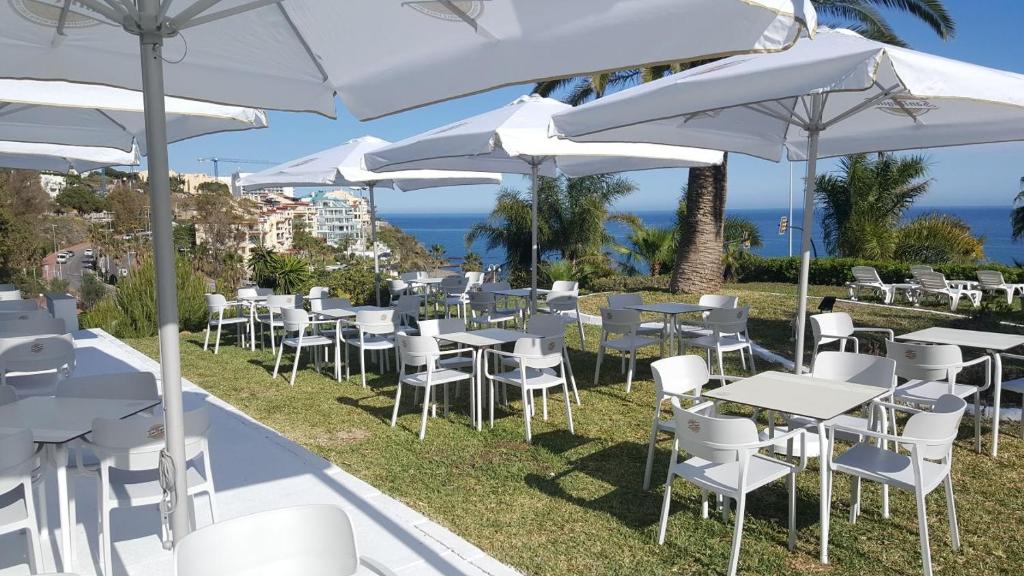 Un montón de mesas y sillas con sombrillas blancas. en First Flatotel International, en Benalmádena