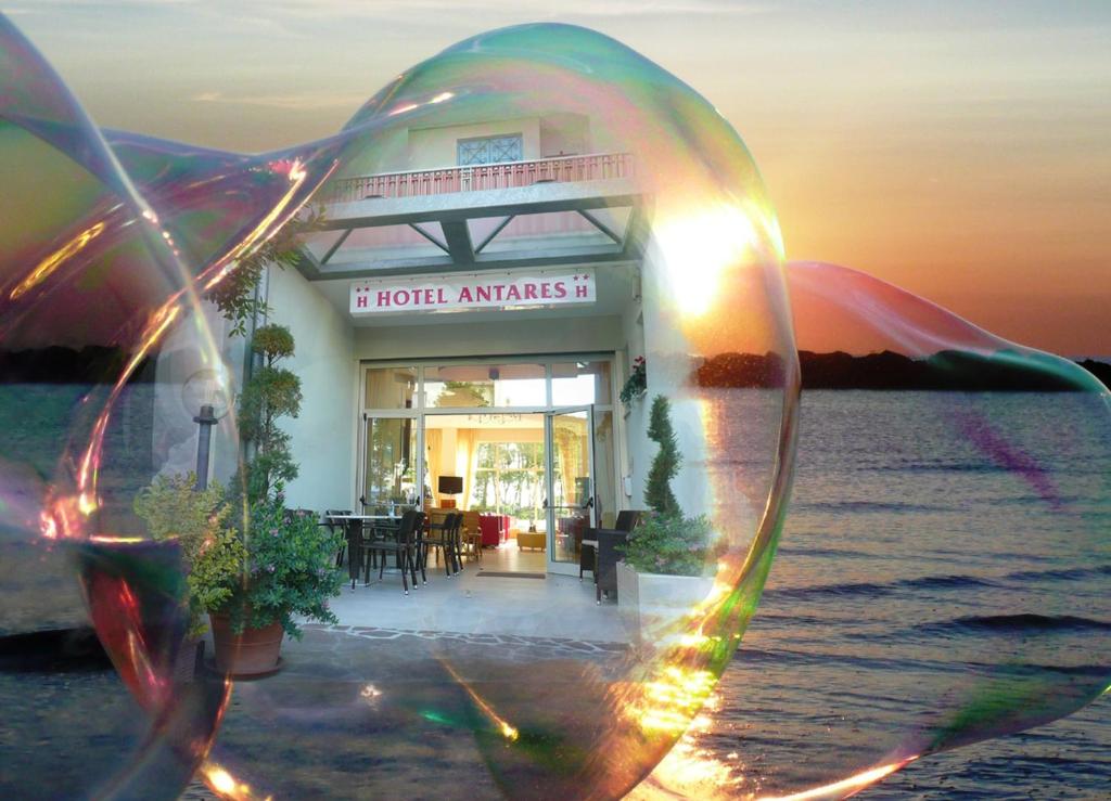 Hotel Antares في ميكيلي: كأس من النبيذ أمام الفندق على الماء