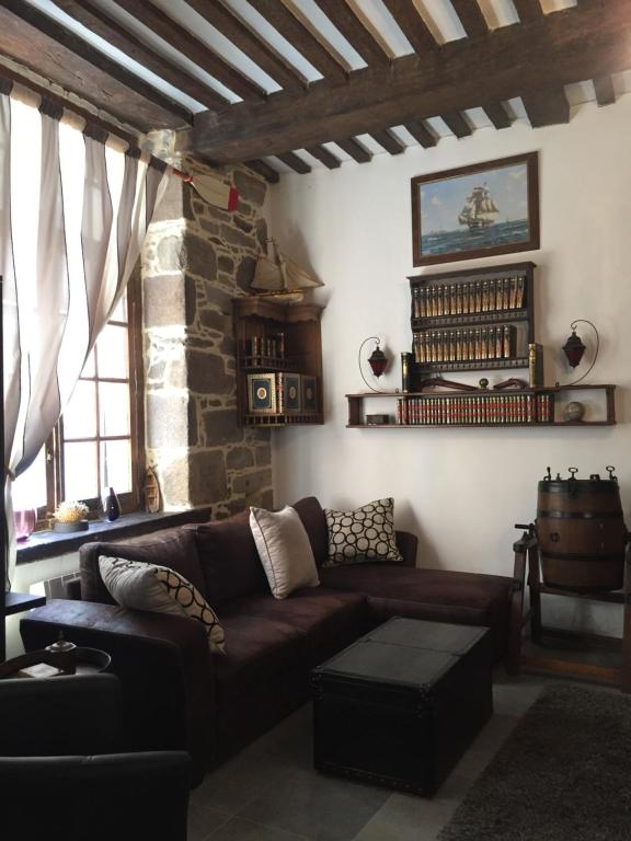 - un salon avec un canapé brun et un mur en pierre dans l'établissement Le 1684, à Saint-Malo