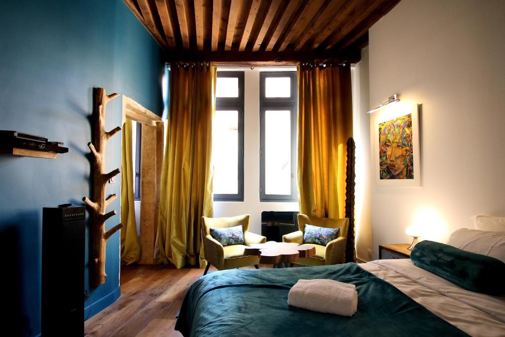 a bedroom with a bed and chairs and a window at 3e secret en plein coeur du Vieux Lyon in Lyon