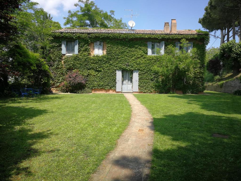 a green building with a white door and a grass yard at Alloggio Al San Girolamo in Longiano