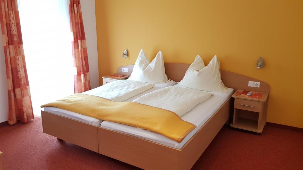 1 dormitorio con 1 cama con sábanas y almohadas blancas en Roseggerhof, en Sankt Kathrein am Hauenstein