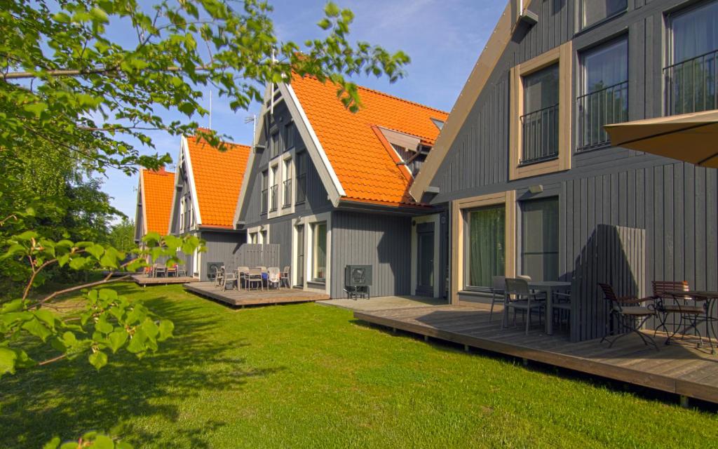 a house with an orange roof and a yard at Nidos Namai in Nida