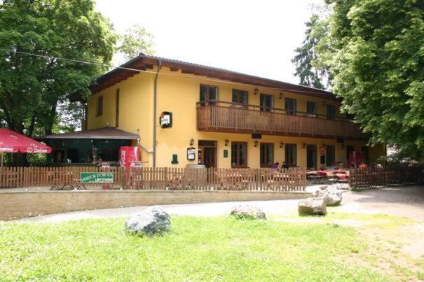 - un bâtiment jaune avec un balcon et quelques rochers dans l'établissement Penzion Pohoda, à Lultsch