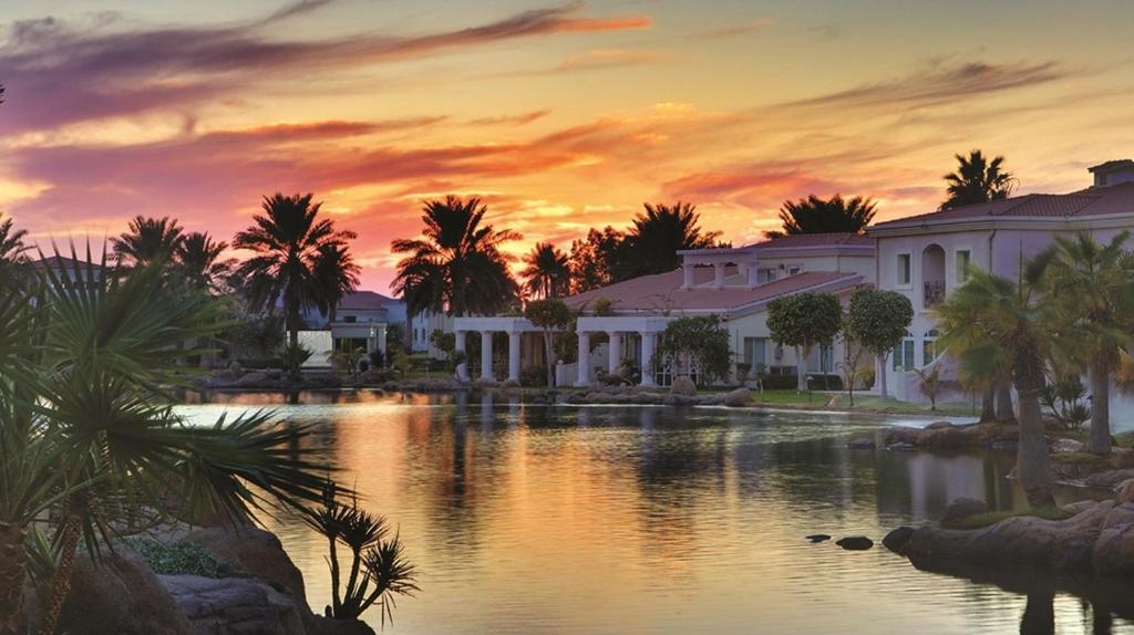 a resort with a lake and palm trees at sunset at Sunset Beach Resort Marina & Spa in Al Khobar